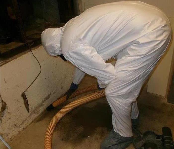 A person vacuums the room wearing a protective body suit.