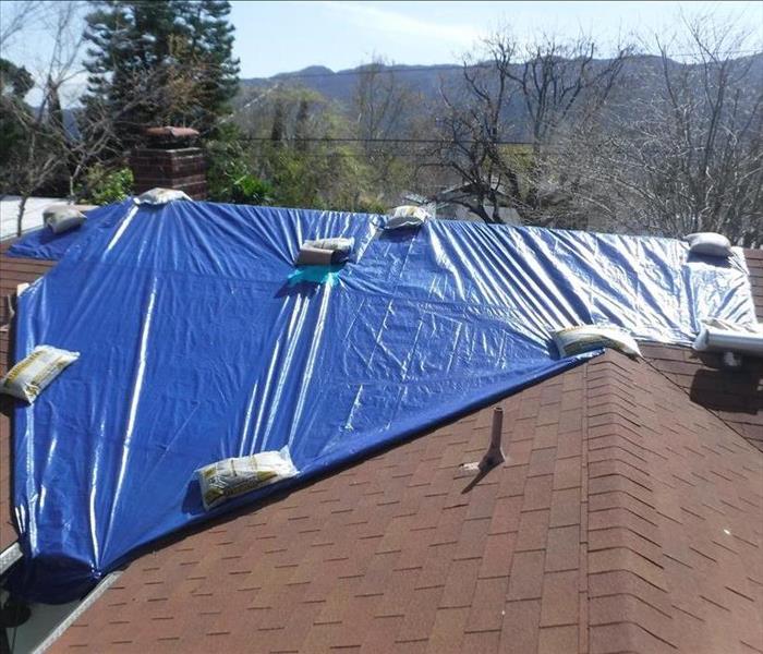 Tarp covering the roof of the house, secured with sandbags 